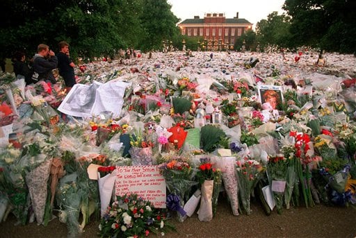 A loss for all: Unidentified mourners view the large collection of flowers that have been left at the gates of Kensington Palace, London before the start of the funeral procession for Princess Diana.