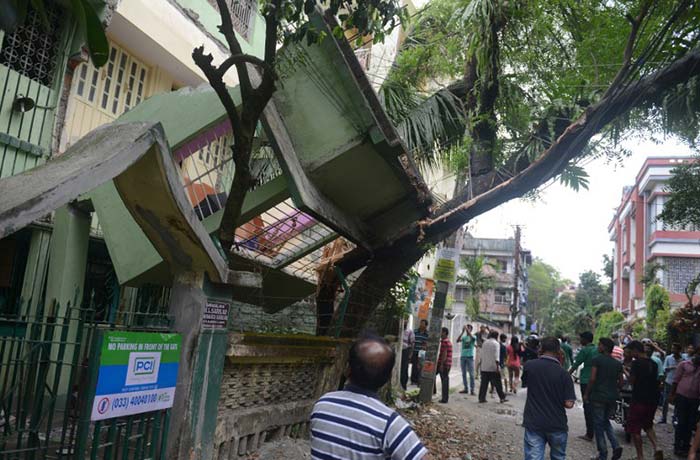 Indian bystanders look at a collapsed house following an earthquake, in Siliguri on April 25, 2015.