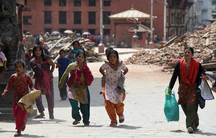 Nepalese residents carry belongings following fresh tremors in Kathmandu on April 26.