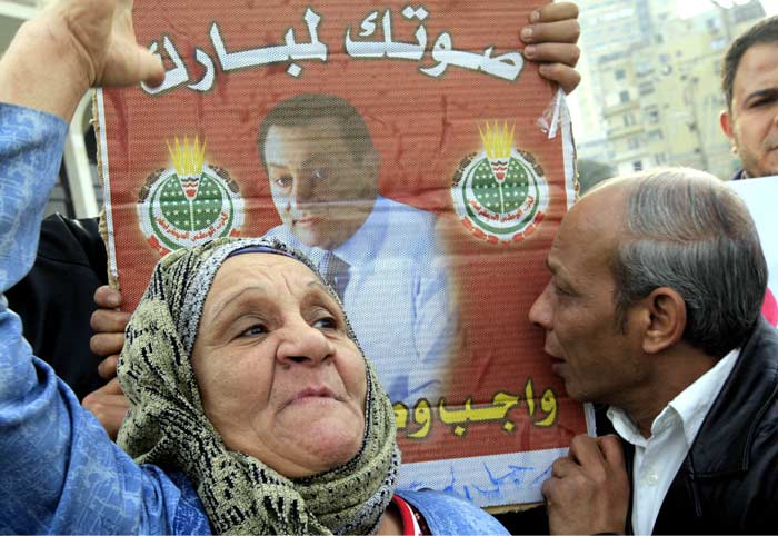 Elderly Egyptian pro-Mubarak supporters shouting supporting slogans and kissing his poster during a march in Cairo. (AP Photo)