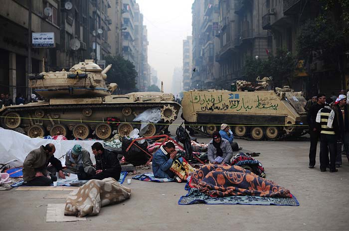 Egyptian anti-goverment demonstrators pray and read newspapers in front of military vehicles in Cairo's landmark Tahrir Square. Arabic graffiti on armoured vehicle reads: "Down with Mubarak... no to Mubarak and no to Suleiman", in reference to Vice President Omar Suleiman. (AFP Photo)