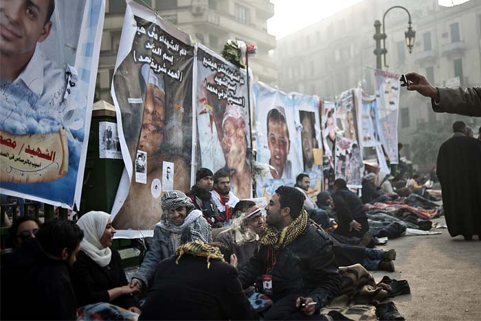 Protesters rest in the early hours of February 11, 2011, in front of posters bearing pictures of people killed during the latest political crisis in Egypt. (AFP Photo)