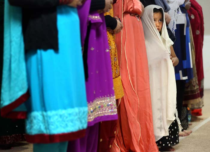 A little girl stands by a family member during a service to celebrate Eid al-Fitr, the three-day holiday marking the end of Ramadan at the Tri-State Islamic Center in Dubuque, Iowa.