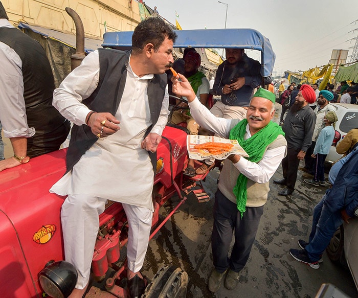 Farmers celebrate with sweets after PM Modi announced the repealing of the three farm laws, at Ghazipur border.