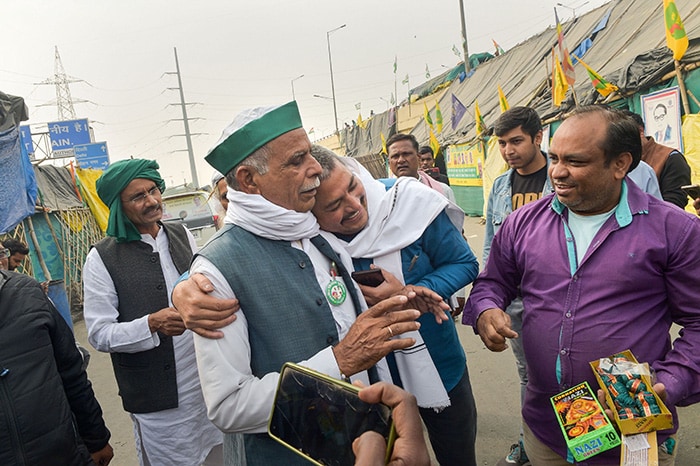 Farmers hug as they celebrate after PM Modi announced the repealing of the three farm laws, at Ghazipur border.