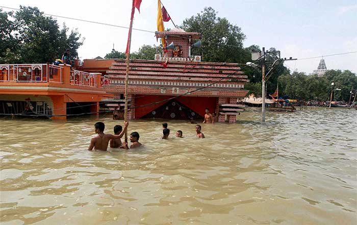 Children swim in river Ganga infront of a submerged Hanuman temple in Allahabad on Saturday. (PTI Photo)