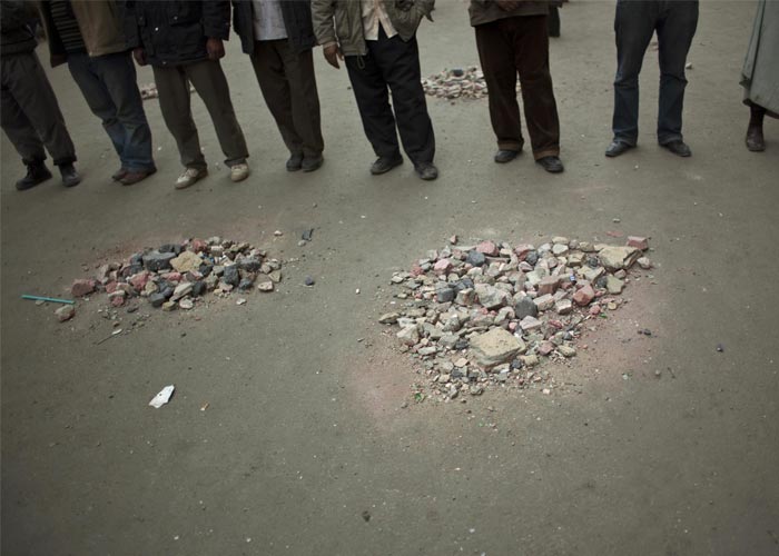 Stones, ready to be thrown, are gathered in piles as anti-government protesters block the street to form a checkpoint at the Tahrir Square. (AP Photo)