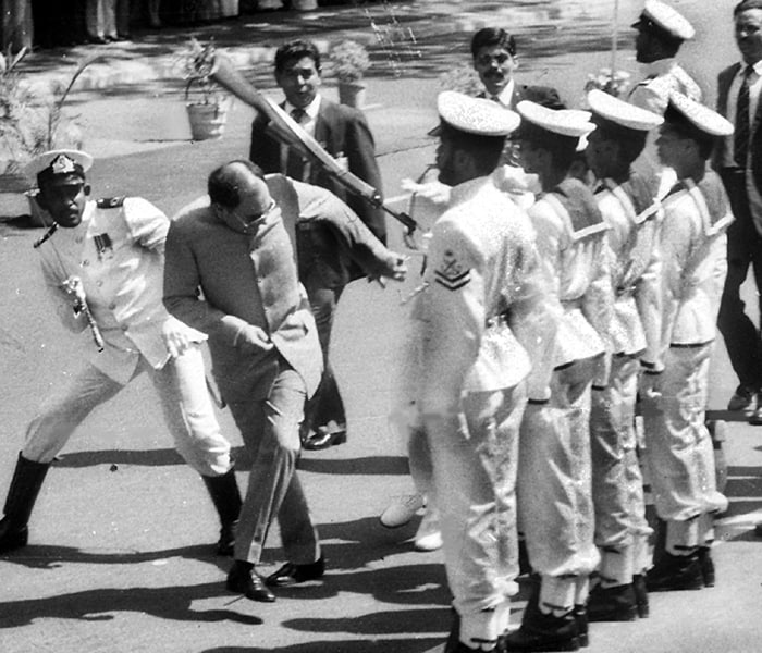 The author says Rajiv "bungled in Sri Lanka; he even fired a minister in a public conference! His role in Shah Bano case and in Babri Masjid incident cannot be denied. Both were big blunders that were irreversible and did long term damage." <br><br>In this picture, Rajiv Gandhi ducks a rifle butt attack by a Sri Lankan naval rating in Colombo on 30 July 1987 after he had signed a controversial peace pact with the Colombo government.<br><br>Singh also criticises him for making the statement "When a big tree falls, the earth is bound to shake..." during anti-Sikh riots in Delhi triggered by the assassination of Indira Gandhi in 1984.