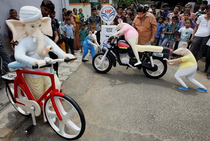 An artists take on increased fuel prices as he makes an idol of Lord Ganesh using bicycle and his mouse on motor-bike at a filling station in Ahmedabad.