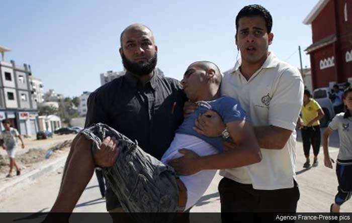 Palestinian employees of Gaza City's al-Deira hotel carry a wounded boy following an Israeli military strike nearby on the beach, on July 16, 2014.