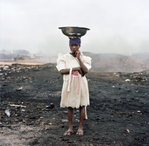 Naasra Yeti, 11 years old, is one of the scavengers in the Agbogbloshie Market. Women and girls often carry bowls of ice to put out fires. (Photo credit: Pieter Hugo for The New York Times)