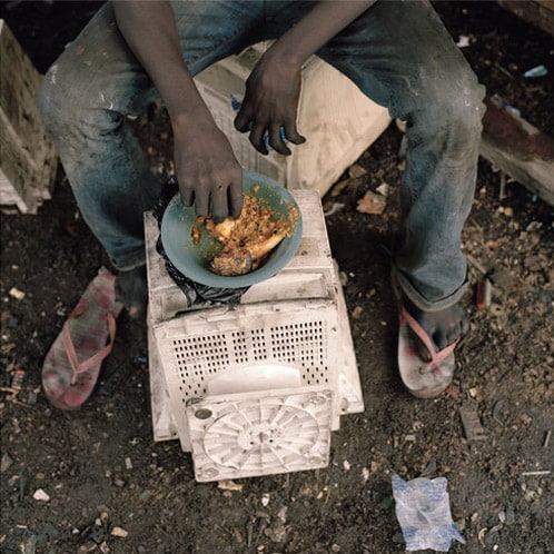 A scavenger stops work for a meal. (NYT Photo)