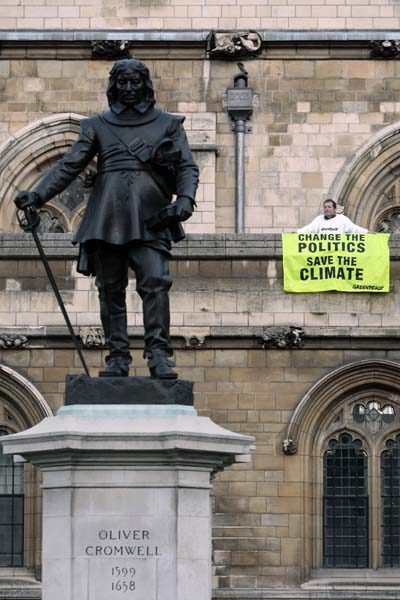 A banner is hung from Parliament behind a statue of Oliver Cromwell after Greenpeace demonstrators scaled the roof of the Houses of Parliament to protest against perceived government inaction on climate change, on October 11, 2009 in London.&nbsp; (AFP Photo)