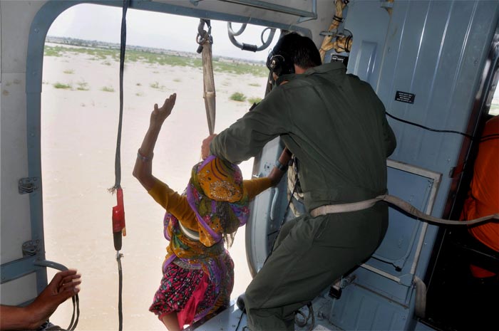 A woman being winched to safety by Air Force personnel from a bus that stands in the flooded waters in Gujarat's Patan.