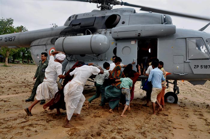 People rush towards an Air Force chopper as it lands in the Gujal village, to be rescued from flood.