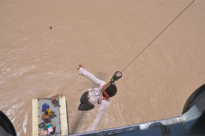 A boy being pulled up by an Air Force helicopter from a bus stuck in flooded water.