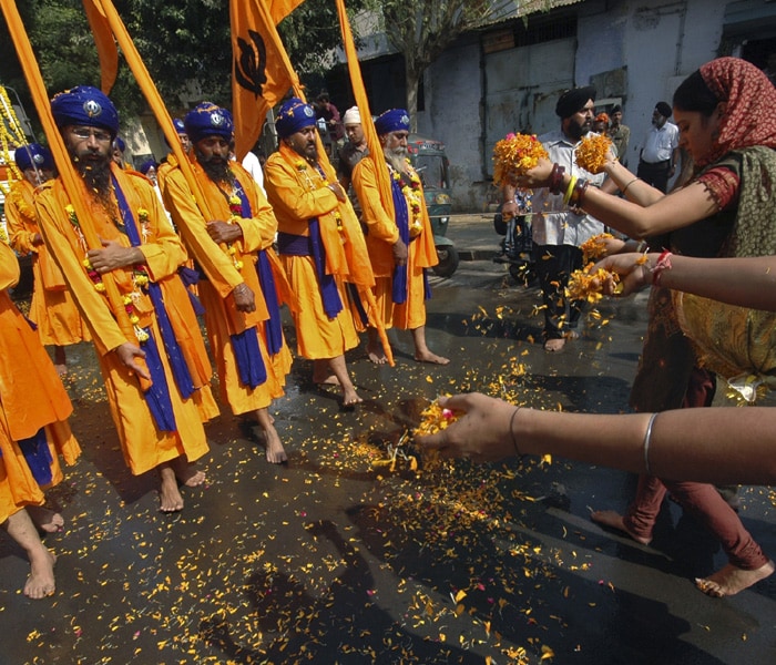 Sikh devotees throw flower petals on the road during a religious procession to mark the birth anniversary of Guru Nanak. (AP Photo)