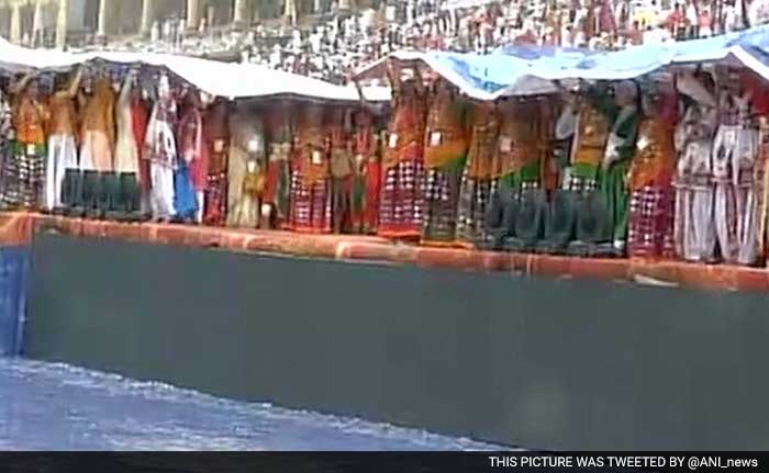 People at the Sri Sri event took refuge under huge tarpaulin sheets away from the mud on the now squishy grounds.