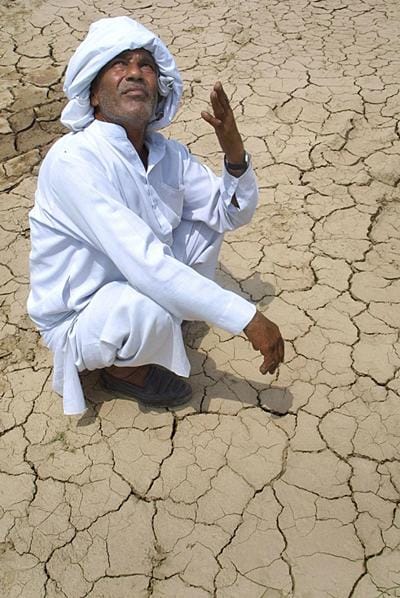 <b>Call to the heavens:</b>A farmer sits on his land and urges the heavens to answer his prayers for monsoon rains with the sun overhead. (AFP image)