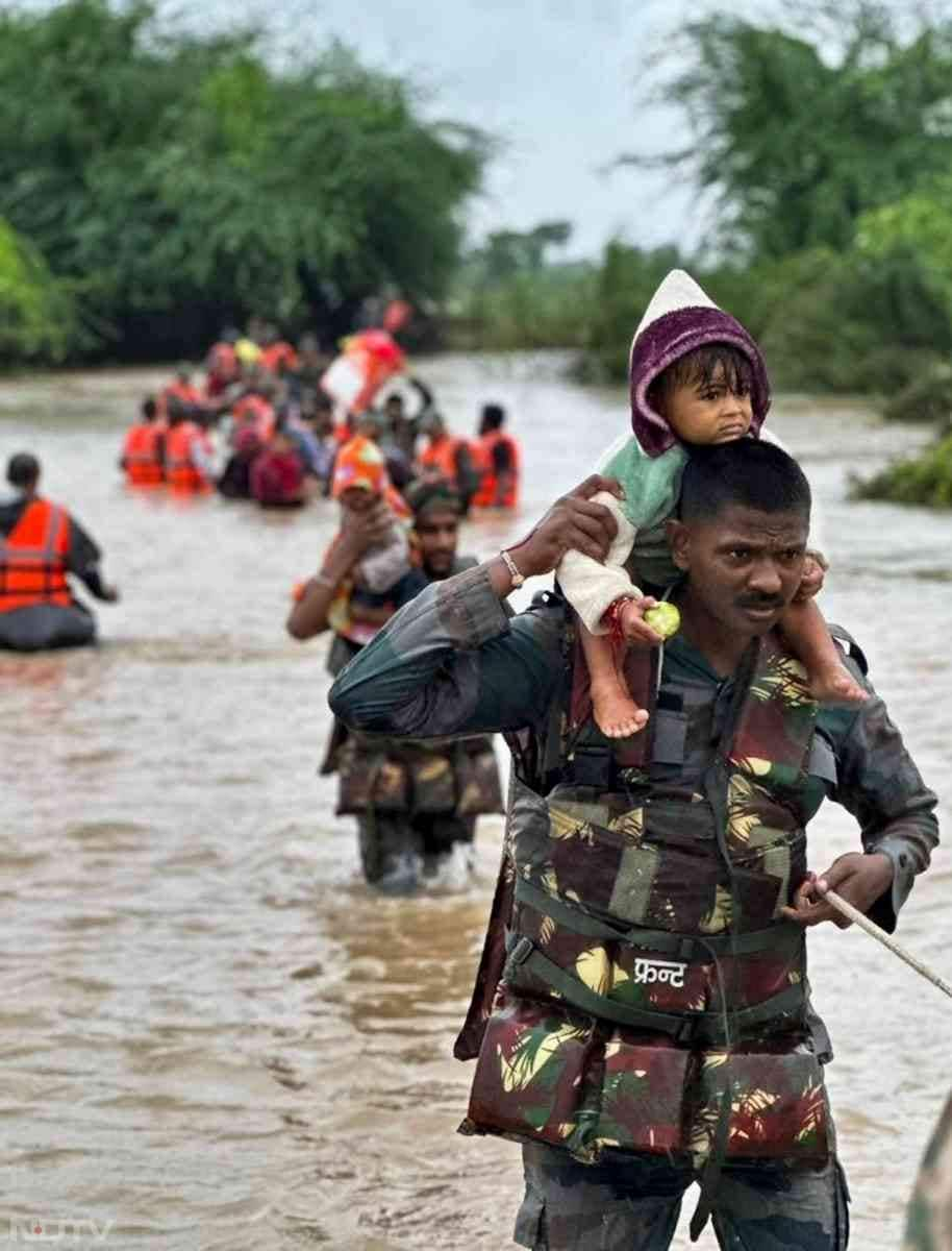 तस्वीरों में देख सकते हैं कि कैसे एनडीआरएफ की टीम वडोदरा में फंसे लोगों को बाहर निकाल रही है. तस्वीर में देख सकते हैं कि एक बचावकर्मी छोटे बच्चे को कंधे पर लेकर सुरक्षित पहुंचा रहा है.