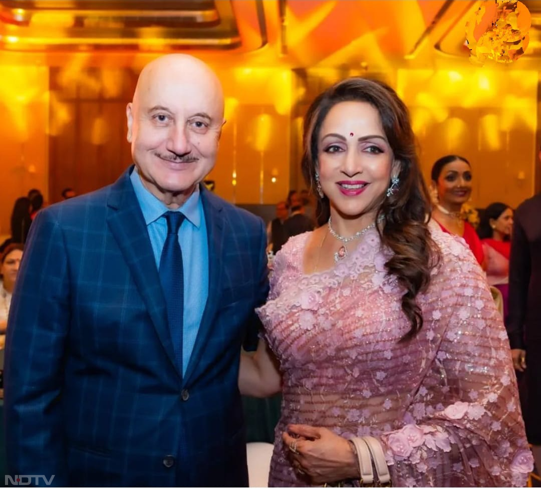 पैपराजी को पोज देते हुए हेमा मालिनी और अनुपम खेर. (फोटो क्रेडिट-इंस्टाग्राम-@dreamgirlhemamalini)