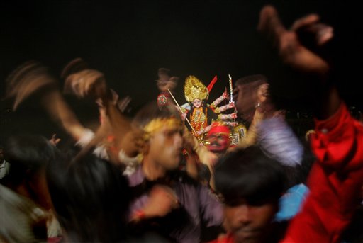 Devotees perform ritual dances before an idol of Hindu goddess Durga, who symbolizes power and triumph of good over evil, on the banks of the River Yamuna in New Delhi, India, Monday, October 2, 2006. The immersion marks the end of five day Durga puja or prayer festival.