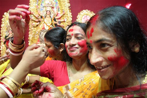 Hindu women put vermilion on each other's face as a ritual before an idol of goddess Durga in Gauhati, India, Monday, October 2, 2006. Five-day Hindu festival Durga Puja will end with the immersion of idols in the rivers Monday.