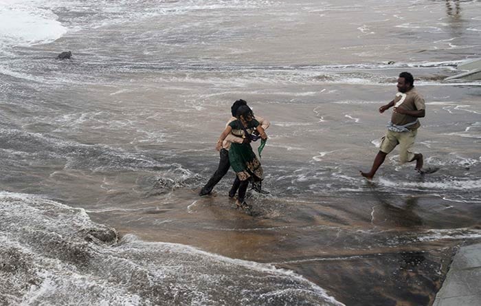 A man, right, rushes to help as another rescues a woman who fell due to strong tidal waves on the Bay of Bengal coast at Gopalpur, Odisha.<br><br>Trees were uprooted and power cables snapped as a powerful cyclone swept through the Bay of Bengal and slammed into the southern city of Visakhapatnam, one of two storms pounding Asia on Sunday.