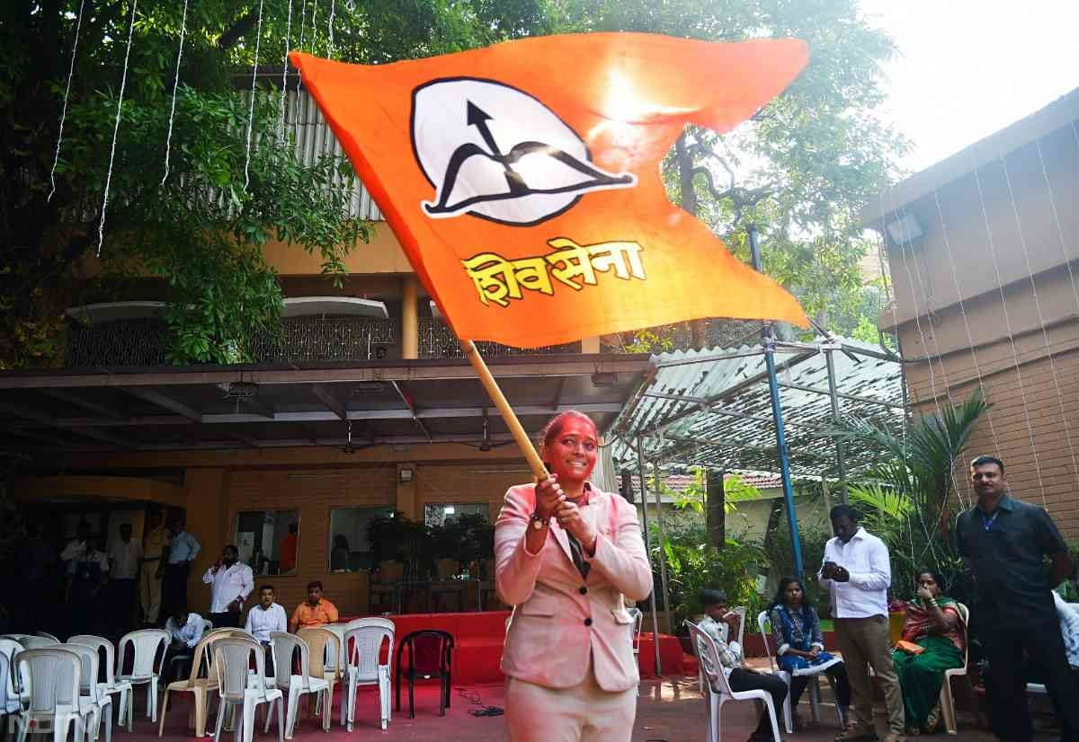 A Shiv Sena supporter waves the party flag outside Varsha Bungalow in Mumbai during the celebrations