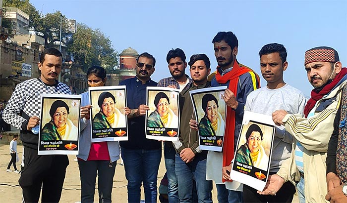 Fans hold the pictures of Veteran Singer Lata Mangeshkar to pay her tribute on her demise, at Assi Ghat, in Varanasi on Sunday. (ANI Photo)