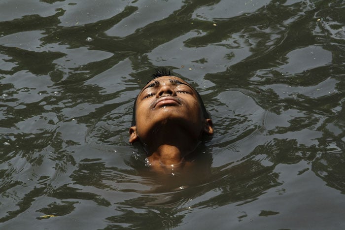 The whole country is reeling under severe heat wave.<br><br> In this picture, a boy cools himself in the polluted waters of a canal to wade off the intense heat. (AFP Photo)