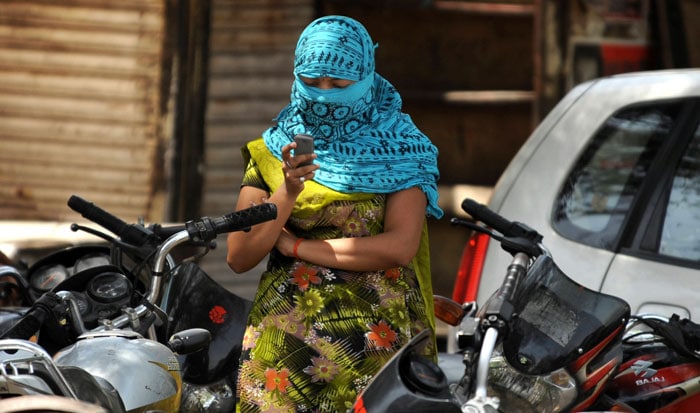 To avoid the scorching heat, a young girl steps out completely covered. (AFP Photo)