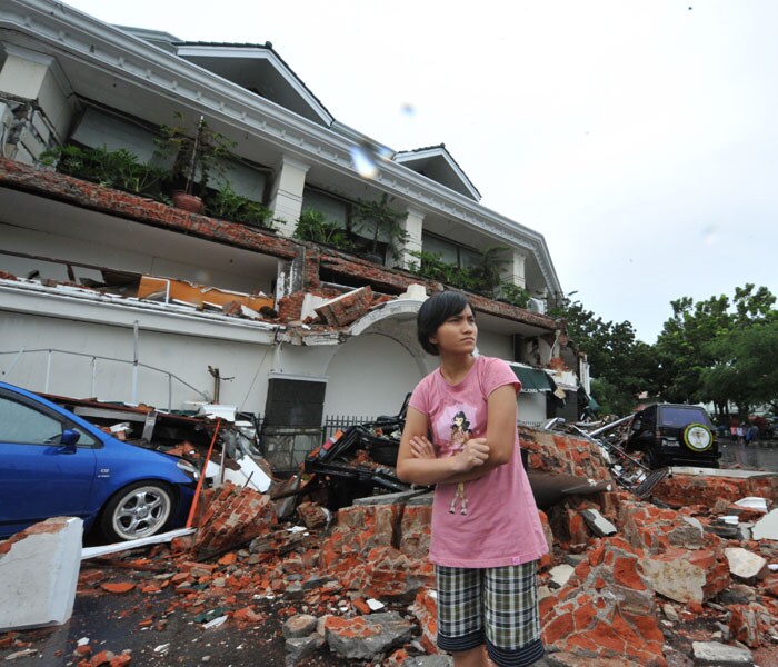 A woman stands next to a colapse hotel in Padang, West Sumatra, on October 1, 2009 after a 7.9 strong earthquake hits the area. AFP PHOTO