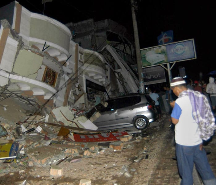 A resident stands next to a building that has collapsed onto a car in Padang on September 30, 2009. Rescue workers raced against time on October 1 to assist victims of a huge earthquake in the flattened Indonesian city of Padang. AFP PHOTO