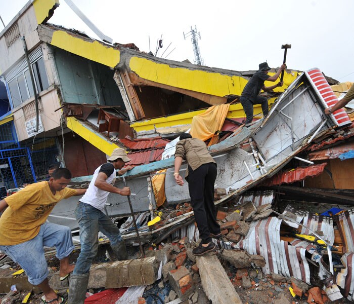 People search for victims from a collapse shop in Padang, West Sumatra, on October 1, 2009 after a 7.9 strong earthquake hits the area. AFP PHOTO