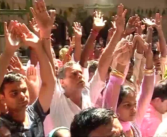 Seen here, devotees of Lord Krishna raise their hands in veneration outside a Krishna temple on the ocassion of Janmashtami.