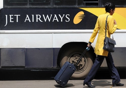 <span class="lh16 fa fs12 fb">A Jet Airways flight attendant walks past a company coach at the city airport in Mumbai on September 8, 2009. The Jet pilots' association says the management is responsible for the current mess. They want a written promise that the sacked pilots will be taken back. (AFP Photo)</span>