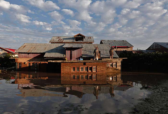 Kashmiri men stand on the roof of their flooded house as they wait to be rescued by Indian army soldiers in Srinagar September 10, 2014. (Reuters)