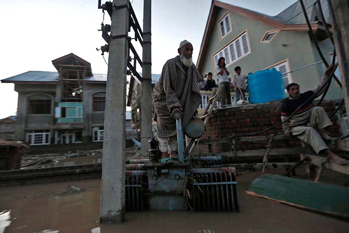 A Kashmiri man stands on an electric transformer as he waits to be rescued in Srinagar on September 10, 2014. (Reuters)