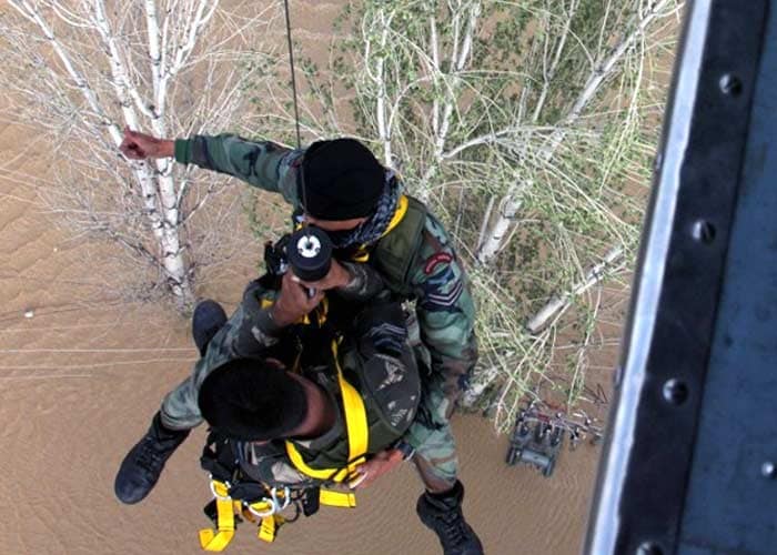 In this handout photo released by Indian Ministry of Defence on September 10, Indian Air Force personnel use a winch to reach residents stranded on a rooftop in Srinagar. (Agence France-Presse)