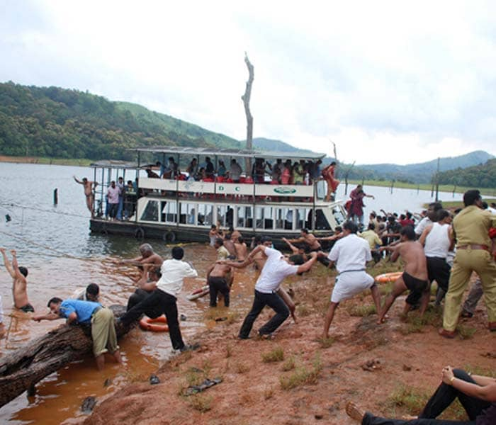 Bystanders and rescue personnel use ropes to pull a vessel to shore at The Thekkady Tiger reserve, some 240 kilometres (149 miles) from Thiruvananthapuram on September 30, 2009, after a boat accident. A tourist boat carrying 76 people in the southern Indian state of Kerala capsized on Wednesday. The boat overturned in the popular Thekkady Tiger reserve, 240 kilometres (149 miles) from Kerala state capital Thiruvananthapuram, when tourists rushed to one side of the vessel to catch a glimpse of a herd of wild elephants.&nbsp;&nbsp;(AFP Photo)