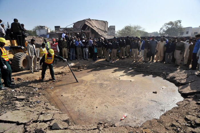 Reports said a car laden with 600kg of explosives rammed the Federal Investigative Agency building, causing a 17-foot crater as an impact of the blast. Neighbouring buildings were also affected.<br><br> In this photo, a Pakistani volunteer examines a crater caused by the car bomb attack.(AFP Photo)