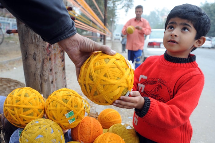 Seen here, a shopkeeper shows balls of coloured kite thread to a young boy by a roadside in Amritsar. (AFP Photo)