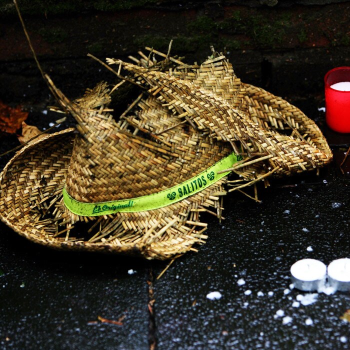 The crushed straw hat can be seen just next to the candles and flowers at the make-shift memorial site. (AFP Photo).