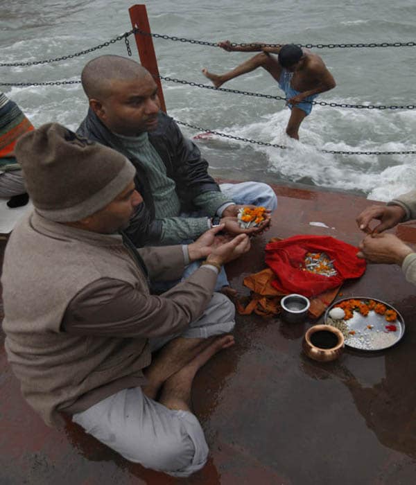 Hindus offer prayers for their ancestors as a man prepares to take a dip in the Ganges. <br/><br/>The Kumbh Mela alternates between Allahabad, Ujjain, Nasik and Haridwar every three years.<br><br>The Mahakumbh is held every 12 years. (AP Photo)