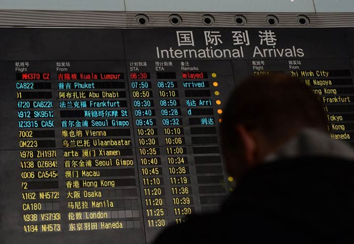 A Malaysia Airlines flight carrying 227 passengers, including five Indians, from Kuala Lumpur to Beijing went missing on Saturday. In the picture, a man stands beside the arrival board showing the flight MH370 (top-red) at the Beijing Airport.