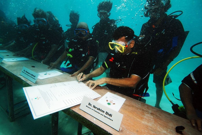 Maldives, October 17, 2009: Fisheries and Agriculture Minister Ibrahim Didi signs the decree of the underwater cabinet meeting off Girifushi Island. Ministers in full scuba gear met on the sea bed to draw attention to the dangers of global warming for the island nation, a tourist paradise featuring coral reefs and white sand beaches with most parts lying less than one metre above sea level. Scientists have warned it could be uninhabitable in less than 100 years. (AFP Image)