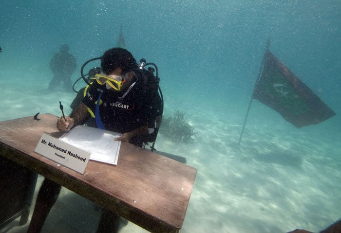 Maldives, October 17, 2009: Maldivian President Mohamed Nasheed signs the decree of the underwater cabinet meeting off Girifushi Island. Ministers in full scuba gear met on the sea bed to draw attention to the dangers of global warming for the island nation, a tourist paradise featuring coral reefs and white sand beaches with most parts lying less than one metre above sea level. Scientists have warned it could be uninhabitable in less than 100 years. (AFP Image)