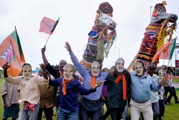 Seen here, BJP supporters wear face mask of Gujarat Chief Minister Narendra Modi during his arrival at Bhubaneswar airpor.