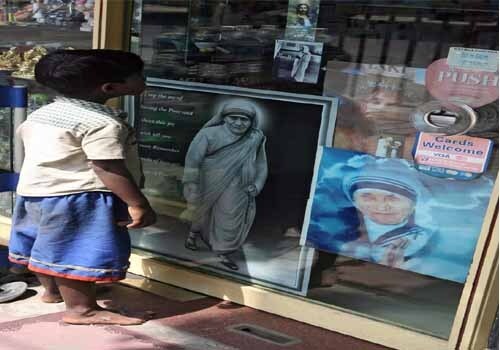 <span class="lh16 fa fs12 fb">A child looks into a gift shop, decorated with images of Mother Teresa in Kolkata. As the Missionaries of Charity took in increasing numbers of lost children, Mother Teresa felt the need to create a home for them. In 1955 she opened the Nirmala Shishu Bhavan, the Children's Home of the Immaculate Heart, as a haven for orphans and homeless youth. The order soon began to attract both recruits and charitable donations. Its first house outside India opened in Venezuela in 1965 with five sisters. Others followed in Rome, Tanzania, and Austria in 1968; during the 1970s the order opened houses and foundations in dozens of countries in Asia, Africa, Europe, and the United States. (AFP Photo)</span>
